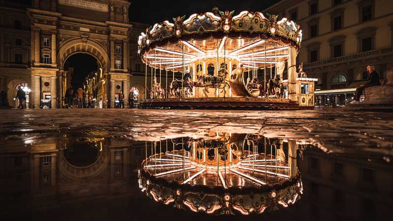 Bright carousel with reflection at night